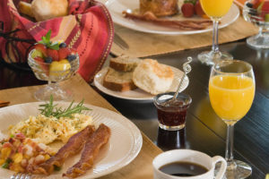 Eggs, bacon, bread, jam, fruit and orange juice on table