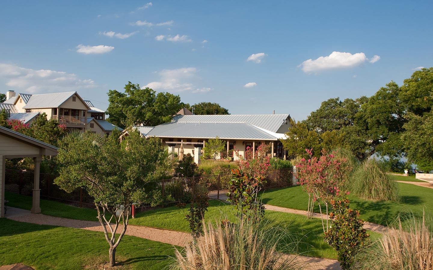 Exterior view of Inn on Lake Granbury property surrounded by trees with multiple cream houses with metal roofs