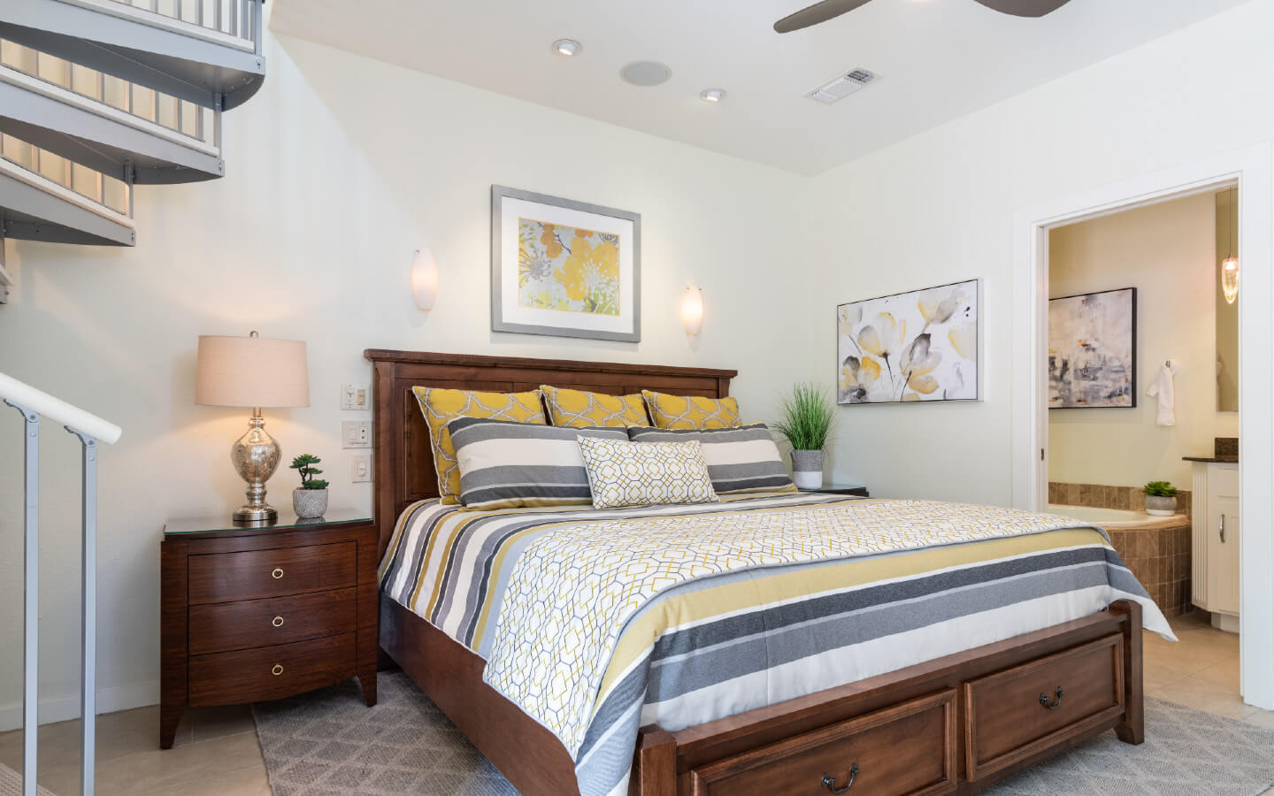 Queen storage bed with two end tables, a ceiling fan, and metal spiral staircase 
