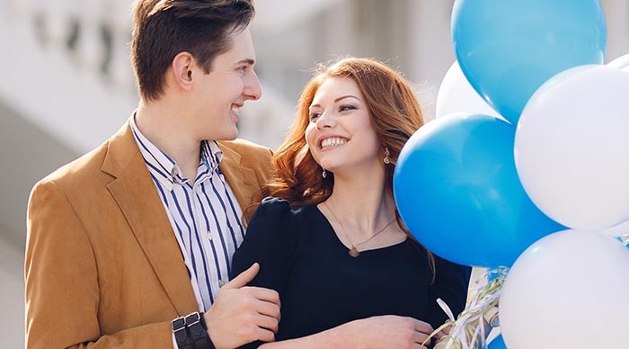 Young couple holding white and blue balloons