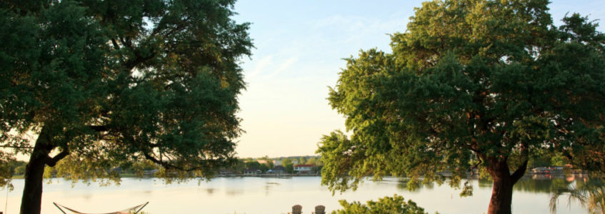 Green lawn with hammock and two chairs overlooking lake