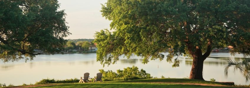 Green lawn with hammock and two chairs overlooking lake