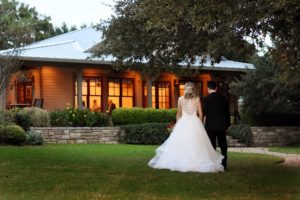 Bride and groom walking into lit building in twilight