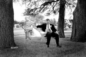 black and white photo of bride and groom on an outdoor swing