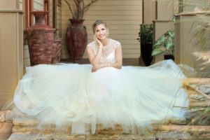 beautiful bride sitting on steps with her dress flared out
