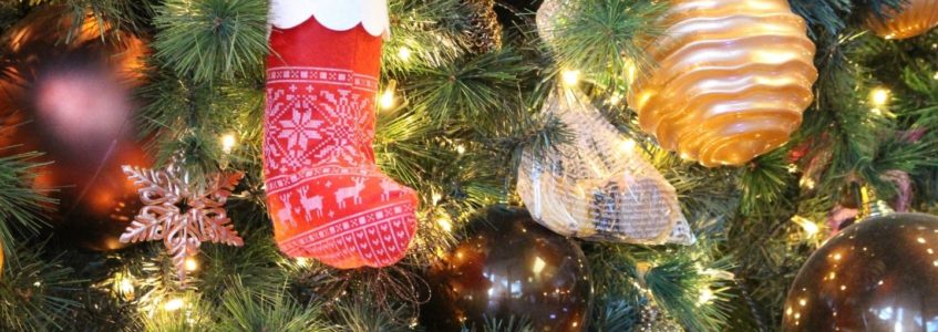 Close-up view of a Christmas tree decorated with mini stockings, twinkling lights, and colored bulbs