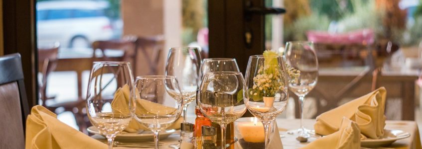 Dining table elegantly set with ivory china, white linen napkins, and wine glasses