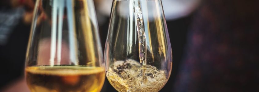 White wine being poured into two wine glasses